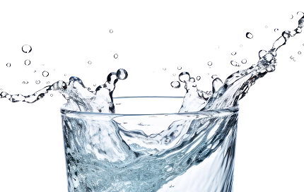 Close-up of fresh water splashing inside a clear glass.